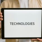Close-up of a person holding a tablet with the word 'Technologies' on the screen.