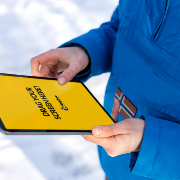 Close-up of hands holding a tablet with a yellow screen in a snowy outdoor setting.
